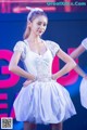 A woman in a white dress standing on a stage.