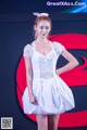 A woman in a white dress standing on a stage.