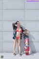 A woman in a red bikini holding a skateboard.