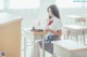 A woman sitting at a desk reading a book.