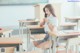 A woman sitting at a desk in a classroom.