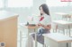 A woman sitting at a desk reading a book.