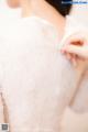 A woman in a white dress is putting on her wedding dress.