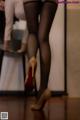 A woman in black stockings and high heels standing in front of a mirror.