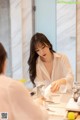 A woman in a white shirt is washing her hands in the bathroom.