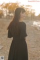 A woman in a black dress standing in a field.