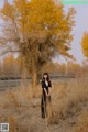 A woman standing in a field next to a tree.