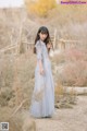 A woman in a long blue dress standing in a field.