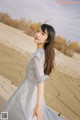 A woman in a white dress standing in the desert.