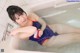 A woman in a blue and orange bathing suit sitting in a bathtub.