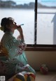 A woman in a kimono blowing bubbles in front of a window.