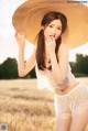 A woman in a straw hat posing in a field.