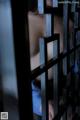 A woman is seen through the bars of a jail cell.