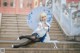 A woman sitting on the steps of a building holding an umbrella.