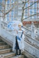 A woman in a white dress holding an umbrella.