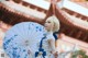 A woman in a white dress holding a blue and white umbrella.