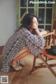 A woman sitting on a wooden chair in a room.