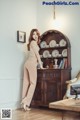 A woman standing in front of a wooden cabinet in a room.