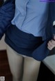 A close up of a person wearing a blue shirt and skirt.