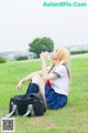 A woman sitting on the grass drinking water from a bottle.