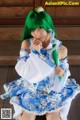 A woman with green hair sitting on a wooden floor.