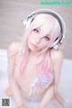 A woman with pink hair wearing headphones in a bathtub.