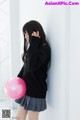 A young woman holding a pink balloon in her hand.