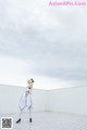 A woman in a white dress standing on top of a roof.