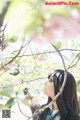 A woman standing in front of a tree with pink flowers.