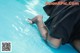 A woman in a black dress is sitting in a pool.