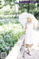 A woman in a white dress holding an umbrella.