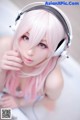 A woman with pink hair wearing headphones. 