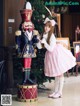 A little girl in a pink dress standing next to a nutcracker.