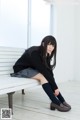 A woman sitting on a white bench in a room.