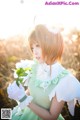 A woman in a green dress holding a white flower.