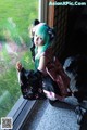 A woman with green hair sitting on a window sill.