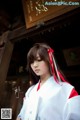 A woman in a white and red kimono holding a book.