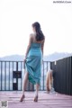 A woman in a blue dress standing on a wooden deck.