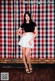 A woman standing in front of a red and white checkered curtain.