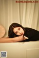 A woman laying on top of a bathtub next to a clock.