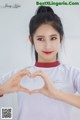 A woman making a heart shape with her hands.