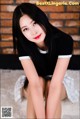 A woman with long black hair sitting on the floor.