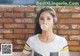 A woman blowing a bubble gum in front of a brick wall.