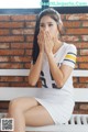 A woman sitting on a bench covering her mouth with her hands.