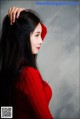 A woman with long black hair wearing a red sweater.