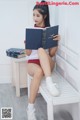 A woman sitting on a bench reading a book.