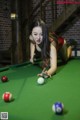 A woman in a red bikini playing pool.