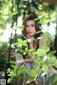 A woman leaning against a fence in the woods.