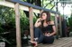 A woman sitting on a wooden deck in a park.