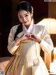 A woman in a white and gold hanbok is posing for a picture.